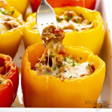 Italian stuffed peppers in a pan with a fork scooping into one.